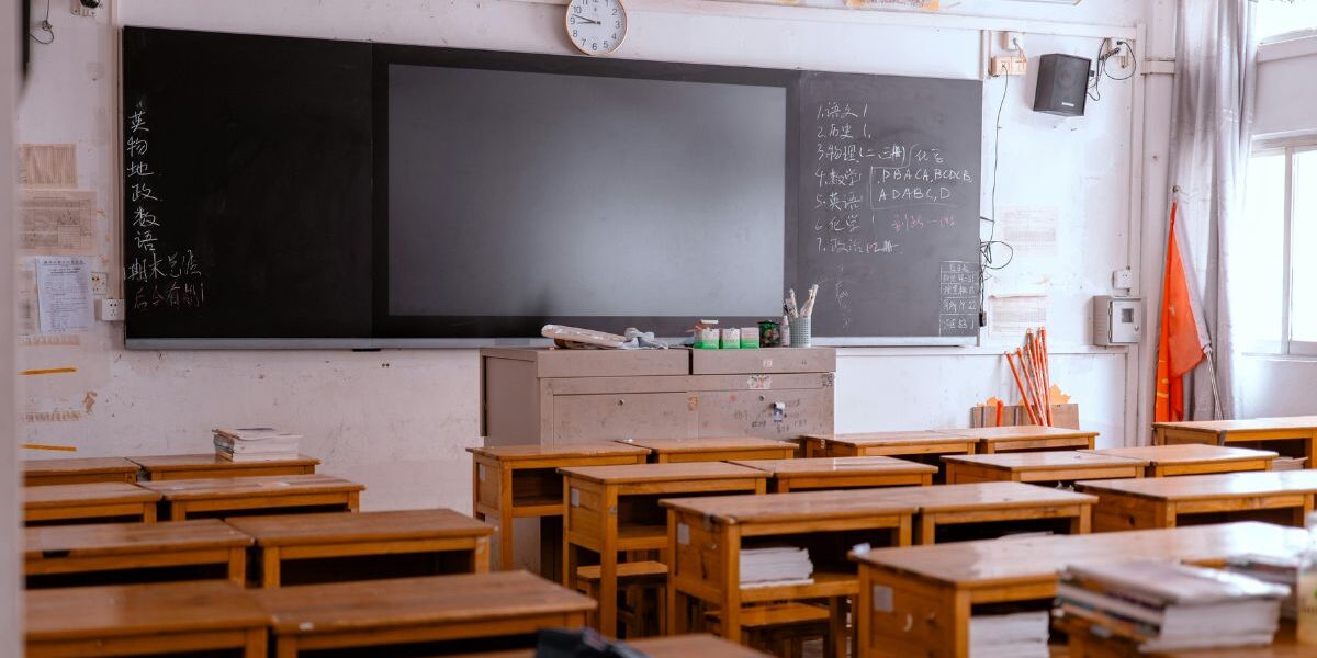 Σχολικός πίνακας και βιβλία πάνω σε θρανίο μέσα σε μια άδεια σχολική αίθουσα