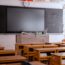 Σχολικός πίνακας και βιβλία πάνω σε θρανίο μέσα σε μια άδεια σχολική αίθουσα