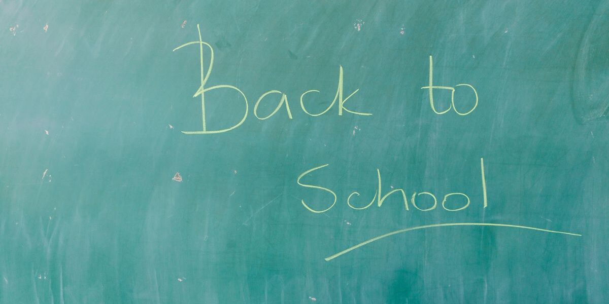 Ένας πράσινος σχολικός πίνακας με τη φράση «Back to School» γραμμένη στο κέντρο με λεπτή, λευκή κιμωλία.