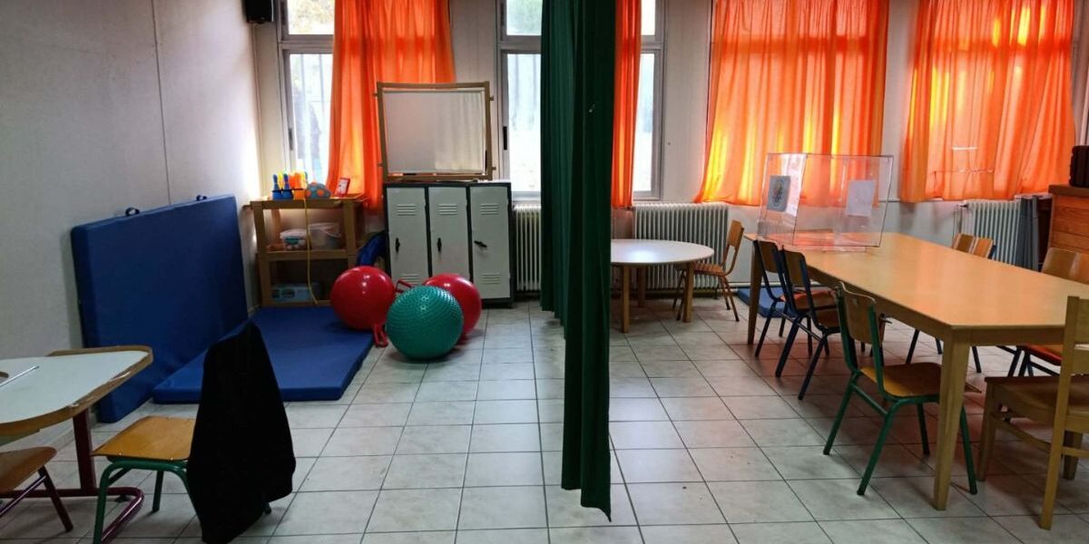 Αίθουσα θεραπειών και διδασκαλίας στα Ειδικά Σχολεία Λευκάδας, η οποία διαχωρίζεται πρόχειρα με μια πράσινη υφασμάτινη κουρτίνα.